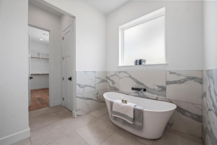 Luxurious primary bathroom featuring a freestanding tub, elegant marble accents, and abundant natural light for a serene retreat.
