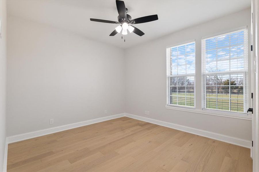 Empty room featuring ceiling fan, light wood finished floors, and baseboards