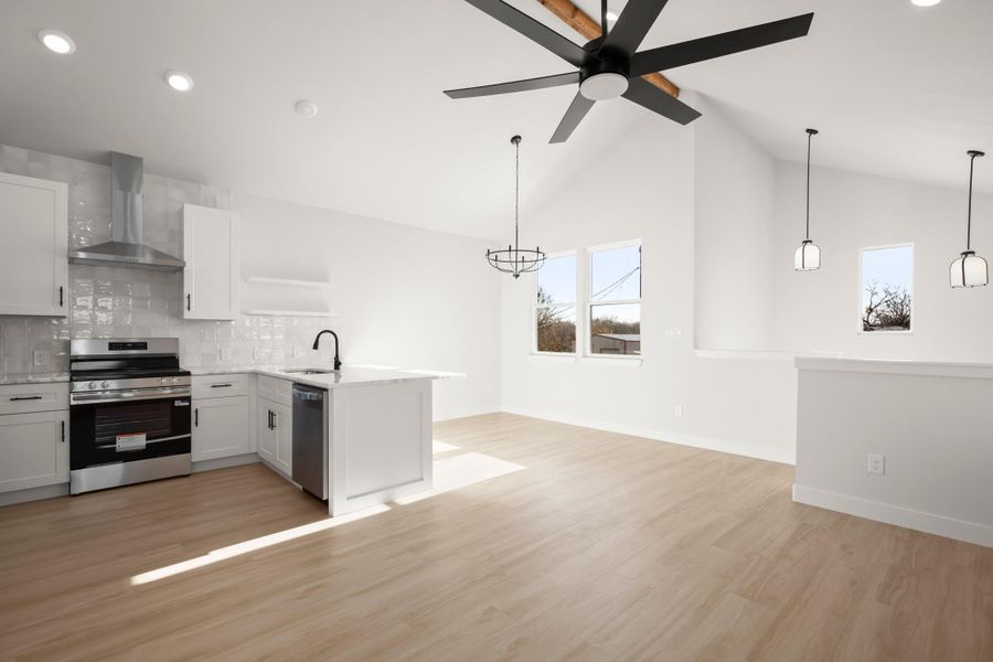 Kitchen with stainless steel appliances, light wood-type flooring, tasteful backsplash, a peninsula, and white cabinets