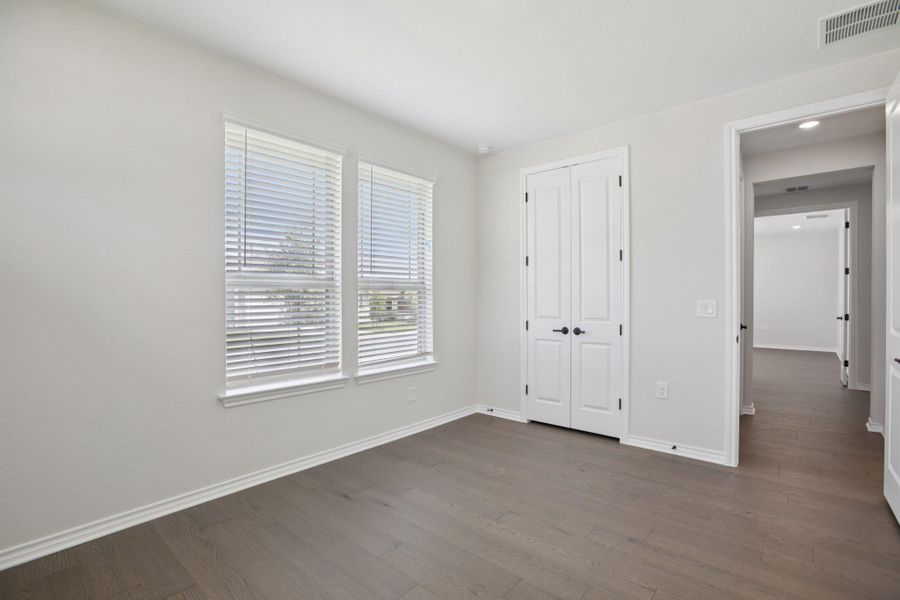Unfurnished bedroom with dark wood-style floors and a closet
