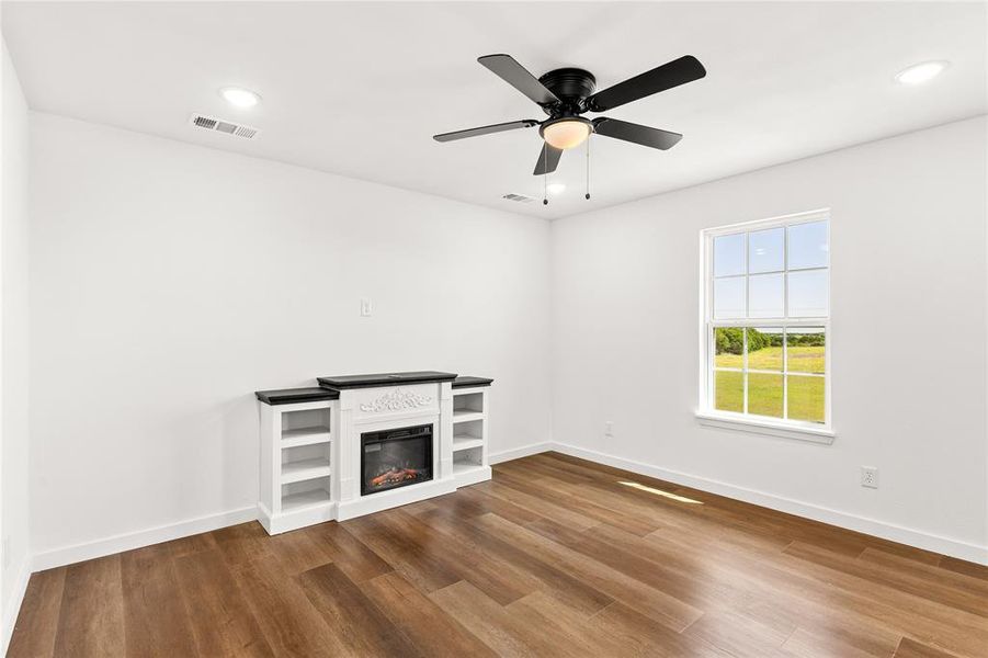 Spacious room featuring wood-finish flooring, a ceiling fan with integrated lighting, and recessed ceiling lights