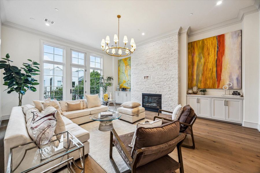 The lavish living room, complete with custom built-ins, stacked stone fireplace, and floor-to-ceiling windows. Twelve-foot ceilings, elegant crown moulding, and understated chandelier by Ziba create warmth and elegance. The lavish living room, complete with custom built-ins, stacked stone fireplace, and floor-to-ceiling windows. Twelve-foot ceilings, elegant crown moulding, and understated chandelier by Ziba create warmth and elegance.