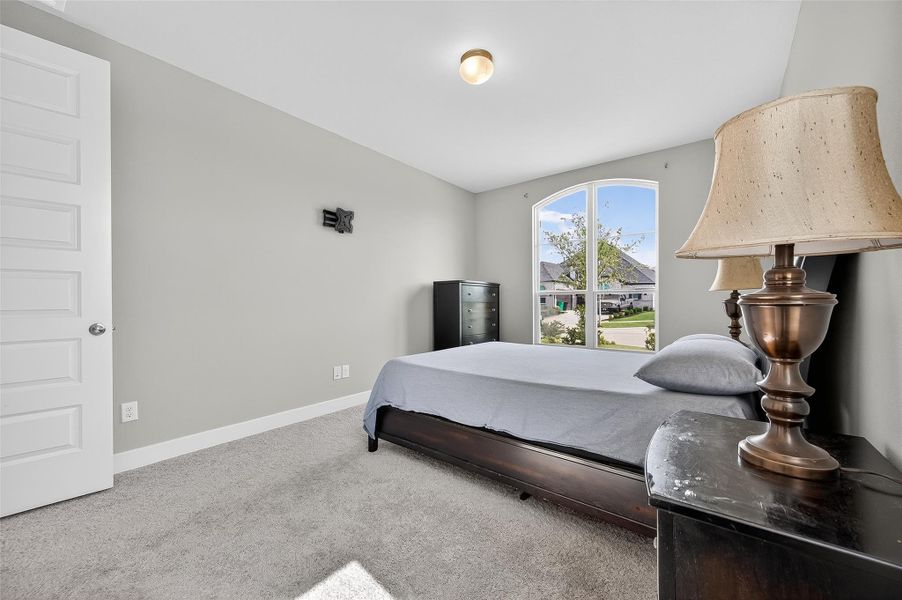 This cozy bedroom features a serene color palette and an arched window. Perfect as a guest suite, home office, or relaxing retreat.