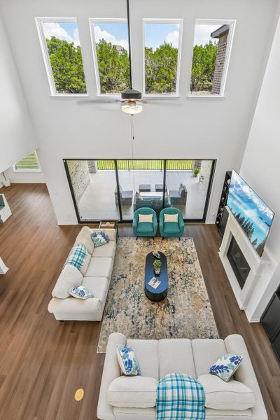 Grand living room features soaring ceilings, a stately fireplace, and seamless outdoor access.