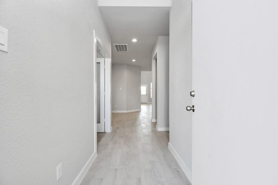 Greeted by a elegant glass front door (to be installed), the entrance beckons with high ceilings, adorned with elegant wood-look tile flooring and oversized baseboards. Sample photo of completed home with similar floor plan. Actual colors and selections may vary.