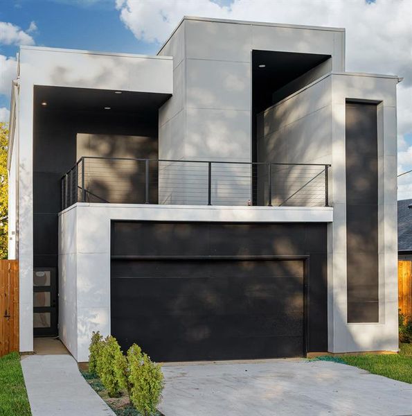 View of front facade featuring a garage, stucco siding, and driveway
