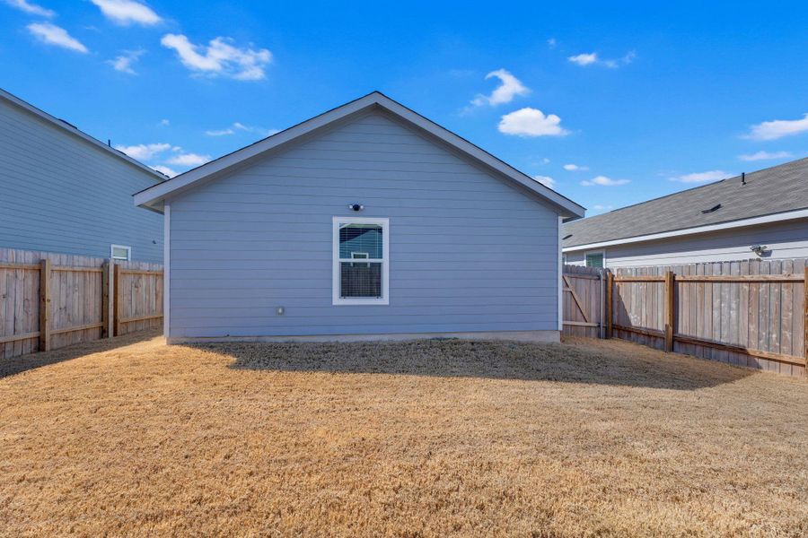 Backyard show casing the back of the house. That window is the primary bedroom.