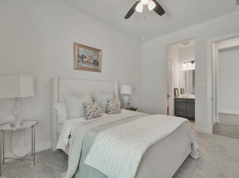 Bedroom featuring light colored carpet, ensuite bath, and ceiling fan Bedroom featuring light colored carpet, ensuite bath, and ceiling fan