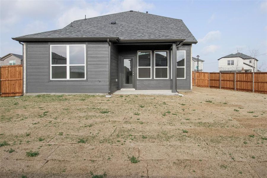 Back of house with a fenced backyard and roof with shingles