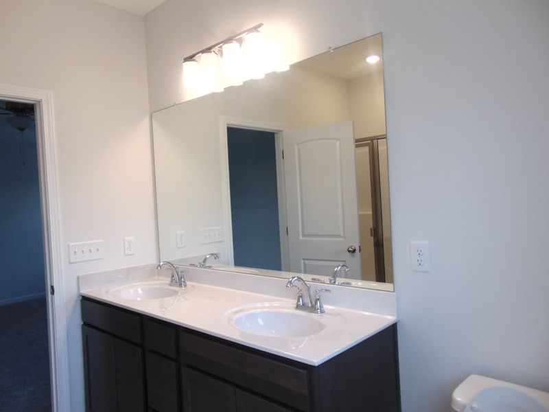 The primary bathroom comes with a two sink, soaking bath tub, shower, and an elongated toilet.