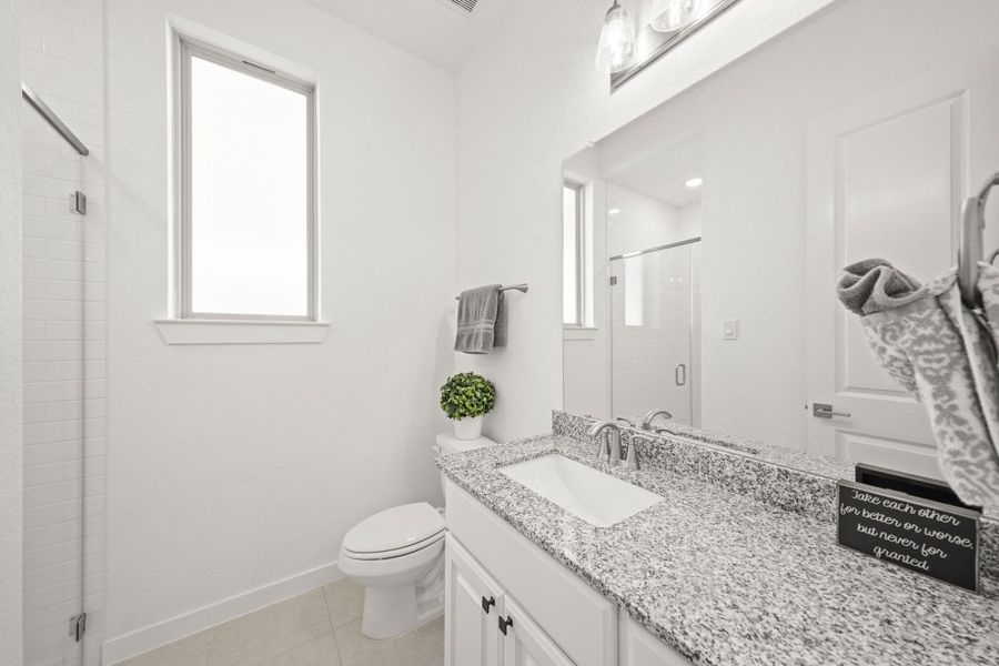 The second bathroom features tile floors, a granite countertop, an opaque-glass window for privacy and a shower with a hexagonal tile floor and subway tile extending to the ceiling.