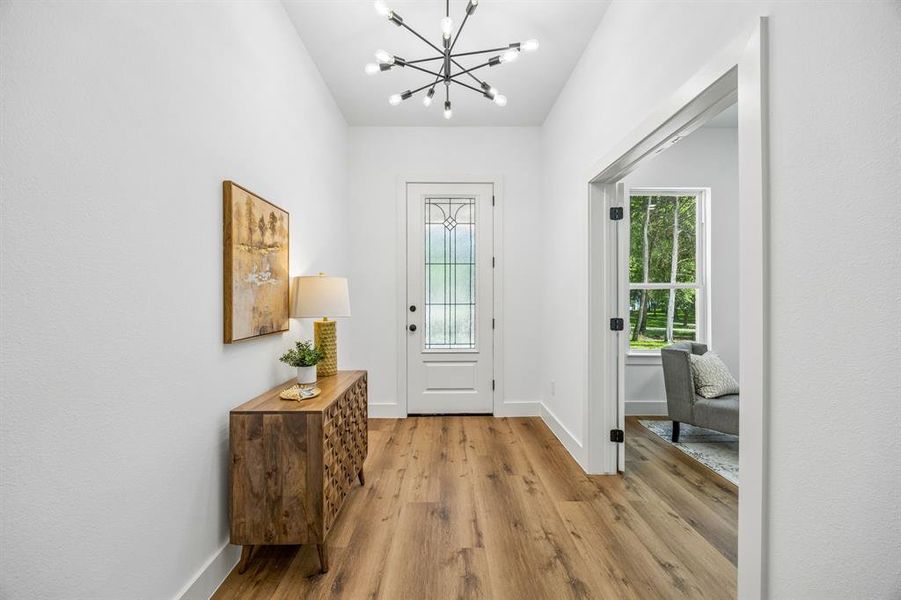 Bright entryway featuring a contemporary chandelier and wide entry to the living room