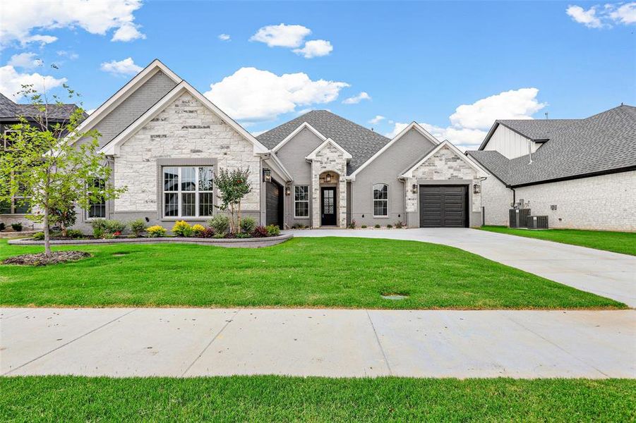 View of front facade with a front yard, a garage, and central AC