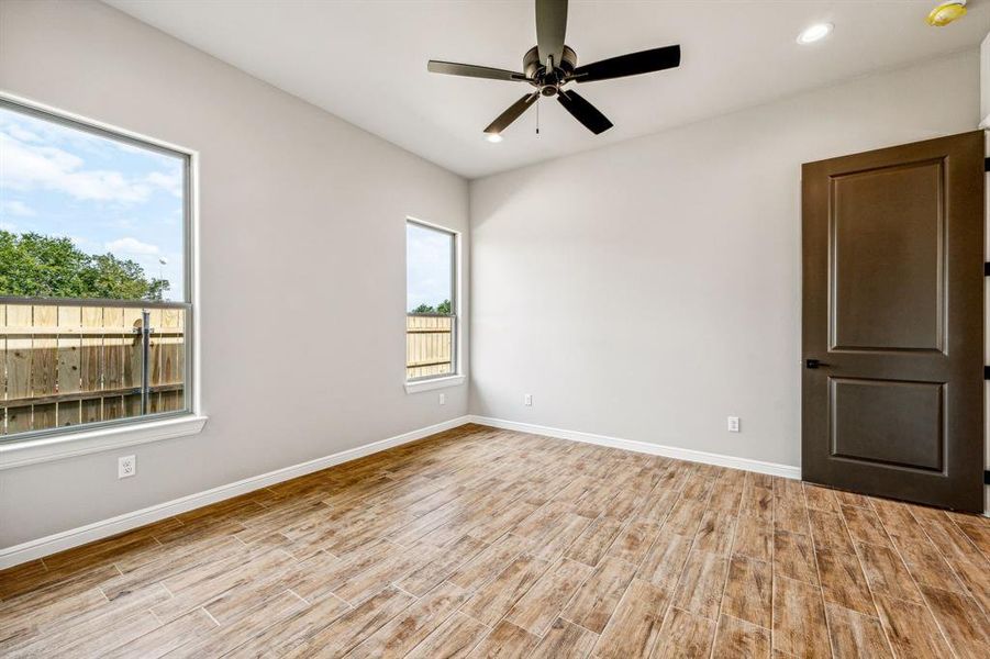 Empty room with light wood-type flooring, a healthy amount of sunlight, and ceiling fan