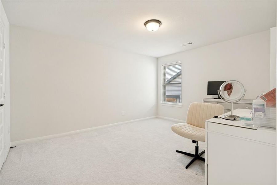 Bright interior space featuring a window with integrated blinds, white painted walls, and light-colored carpet flooring