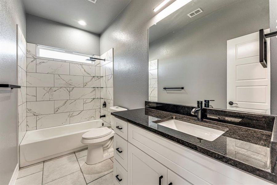 Full bathroom with tile patterned floors, vanity, toilet, and tiled shower / bath