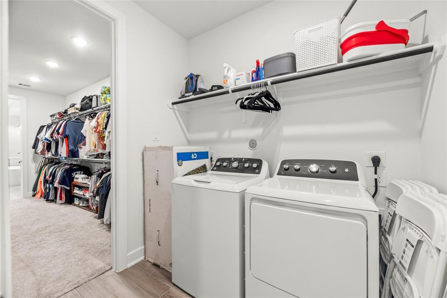 This slick utility room offers shelving for household storage, washer and both gas and electric dryer connections, and access from both the primary walk-in closet and a hallway.