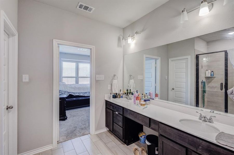 Full bath featuring double vanity, a stall shower, and ensuite bath Full bath featuring double vanity, a stall shower, and ensuite bath