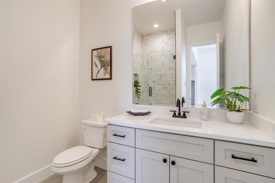 Bathroom with toilet, a stall shower, vanity, and baseboards