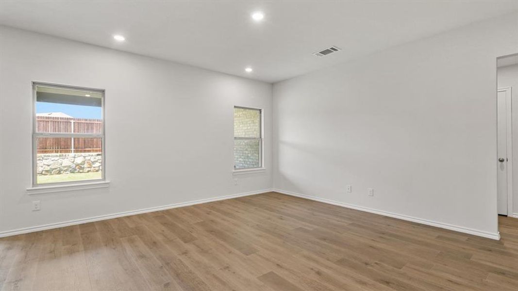 Spacious room featuring wood-finish flooring, recessed lighting, and bright white walls