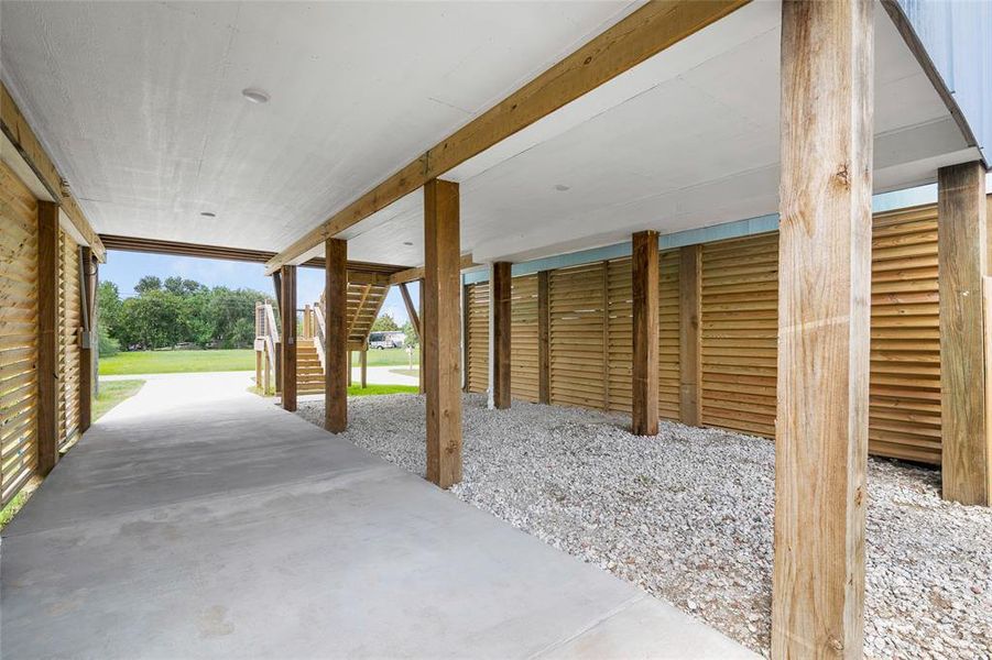 This is the rear view of the covered carport area, offering ample space for parking and outdoor activities, complemented by a louvered wood siding for added privacy and aesthetic appeal.