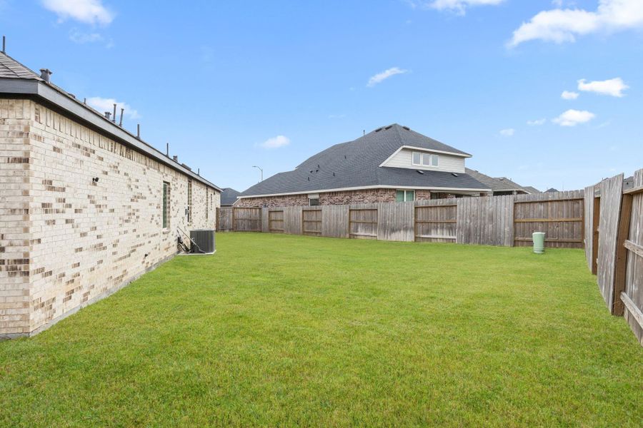 Fully fenced backyard with generous green space offers room for play, pets, or future outdoor additions. Grass has been digitally enhanced for marketing purposes.