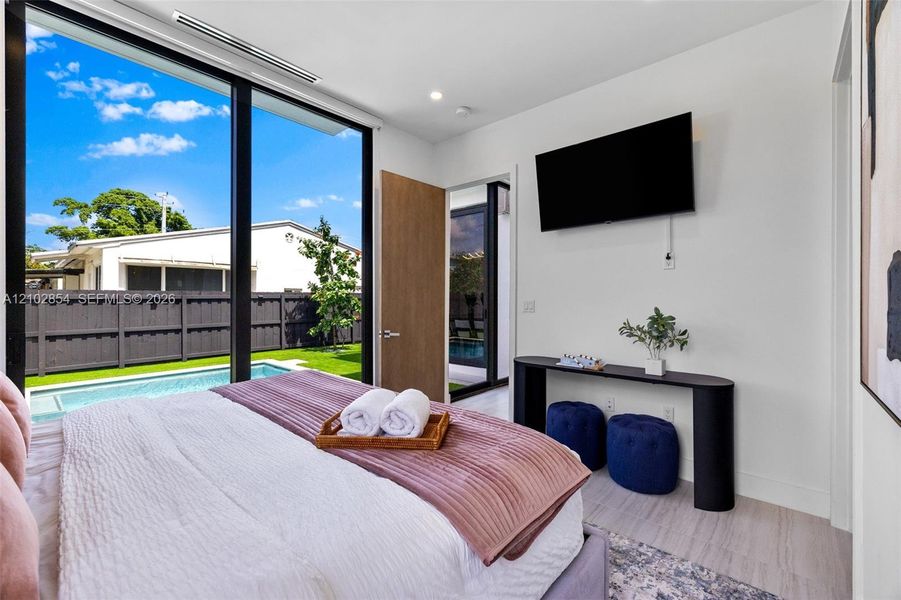 Floor-to-ceiling glass wall, light-toned wood-finish flooring, recessed lighting, and wooden interior door