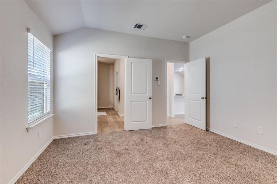 Unfurnished bedroom with light carpet and vaulted ceiling Unfurnished bedroom with light carpet and vaulted ceiling