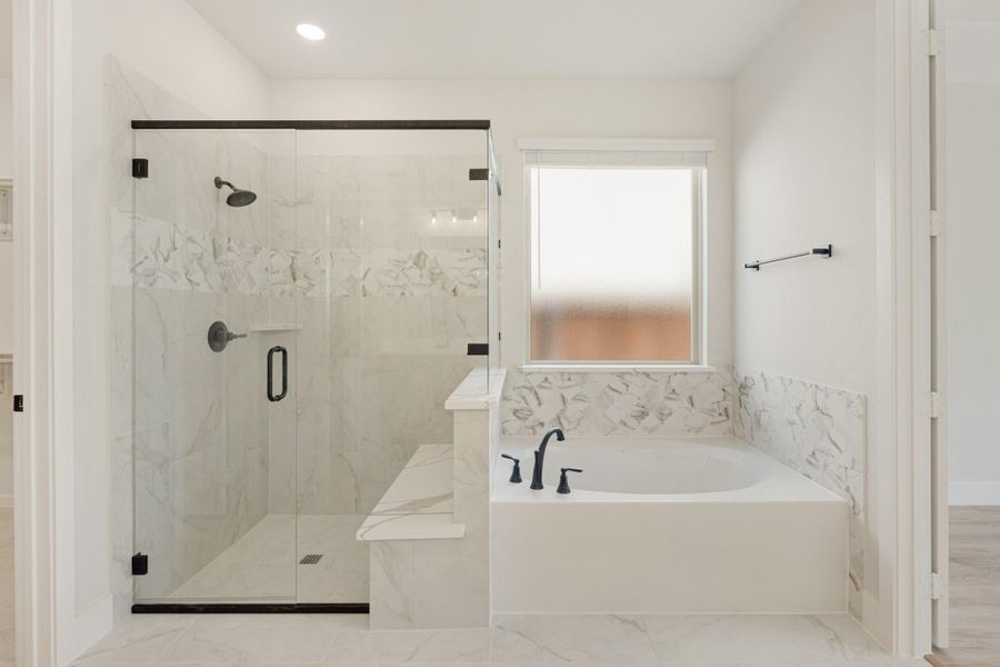 Master bathroom with glass-enclosed shower, soaking tub, marble tile, and matte black fixtures