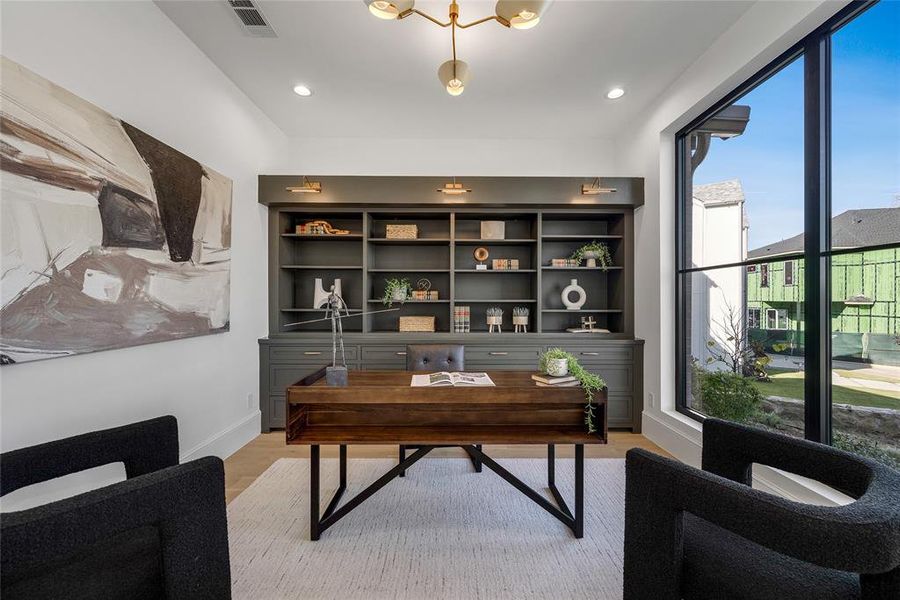 Dedicated space featuring a built-in dark gray shelving unit with integrated lighting, expansive window, wood-finish flooring, recessed lighting, and a modern chandelier