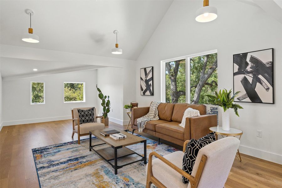 Living area with vaulted ceiling, wood finished floors, and plenty of natural light