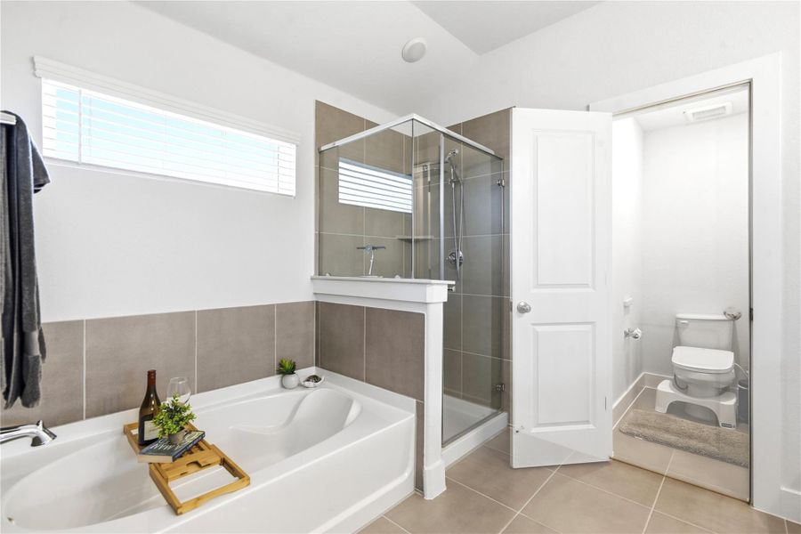 Soaking tub and a spacious glass-enclosed shower elevate this serene primary bathroom.