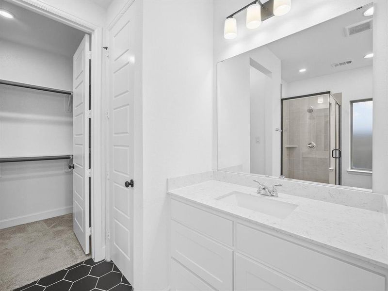 Primary Bathroom with recessed lighting, a shower stall, vanity, dark colored carpet, and a walk in closet Primary Bathroom with recessed lighting, a shower stall, vanity, dark colored carpet, and a walk in closet