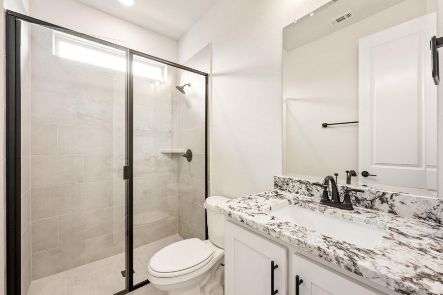 Bathroom with glass walk-in shower, granite countertop vanity, and white cabinets with black hardware Bathroom with glass walk-in shower, granite countertop vanity, and white cabinets with black hardware