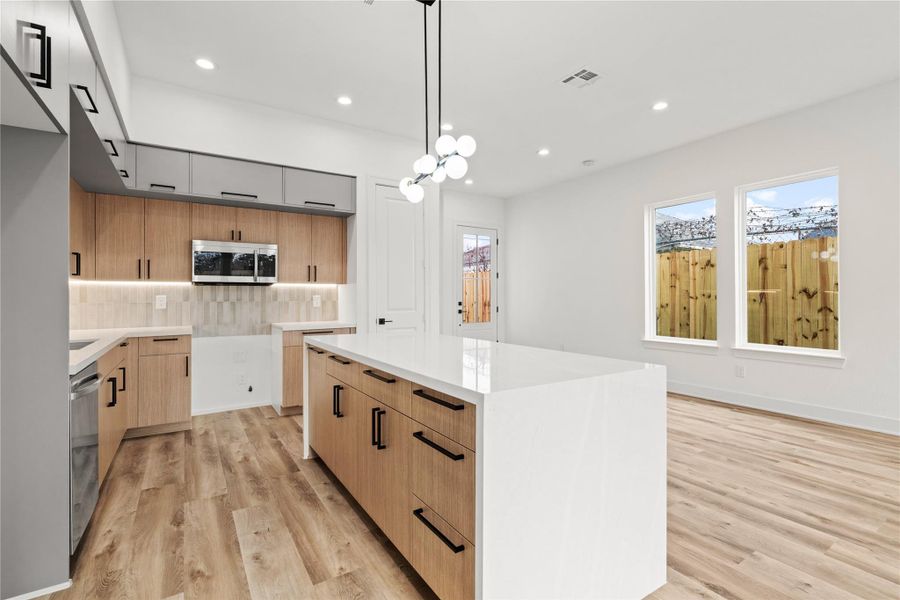 Bright, modern kitchen with a large waterfall island and sleek finishes—perfect for entertaining.