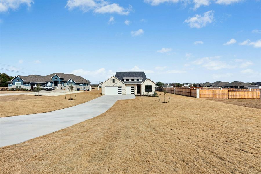 View of front of property featuring a residential view, concrete driveway, stone siding, and a garage