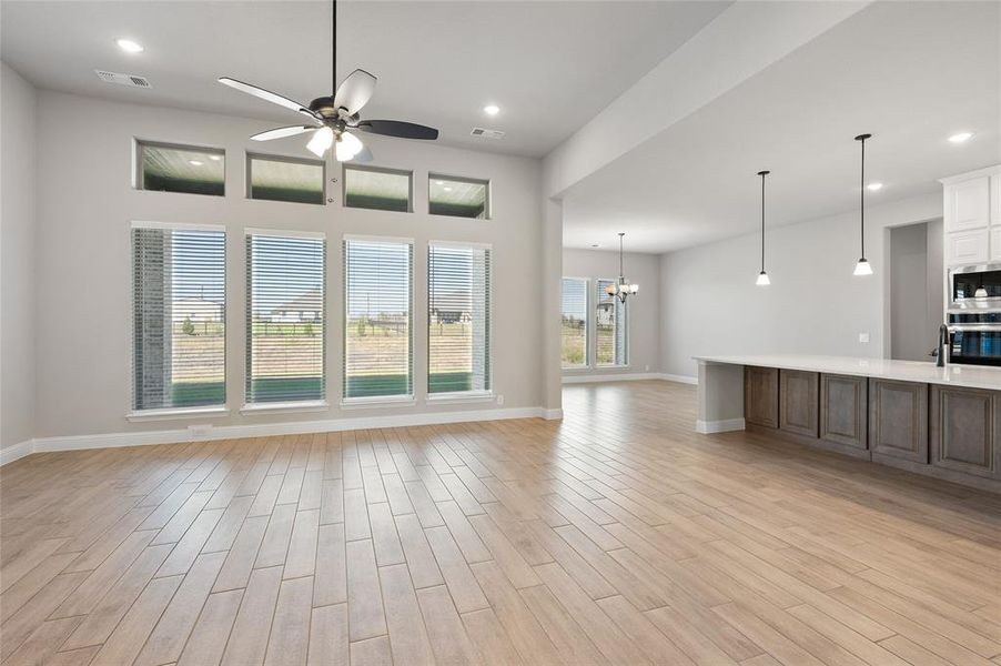 Unfurnished living room featuring a chandelier, recessed lighting, light wood-style floors, and ceiling fan