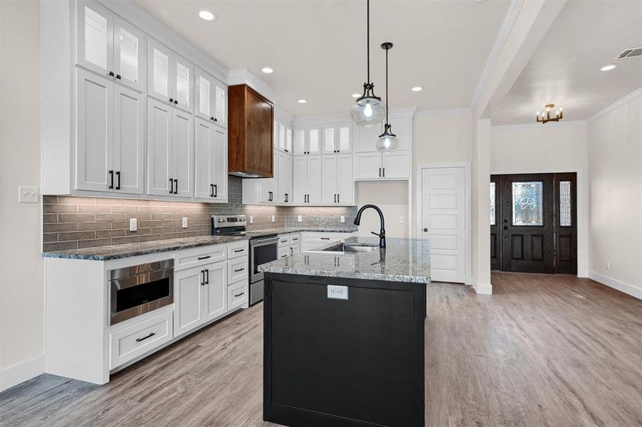 Kitchen with light hardwood / wood-style floors, white cabinetry, ornamental molding, sink, and stainless steel range with electric cooktop