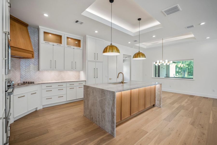 Gorgeous earth tone Taj Mahal Quartzite waterfall kitchen island is the star of the show but is perfectly accompanied by white oak cabinets and gorgeous accent lighting. Gorgeous earth tone Taj Mahal Quartzite waterfall kitchen island is the star of the show but is perfectly accompanied by white oak cabinets and gorgeous accent lighting.