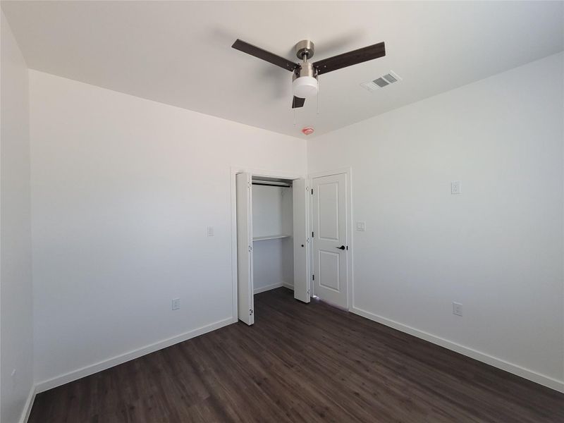 A well-proportioned bedroom with rich hardwood-style flooring and a contemporary ceiling fan awaits.