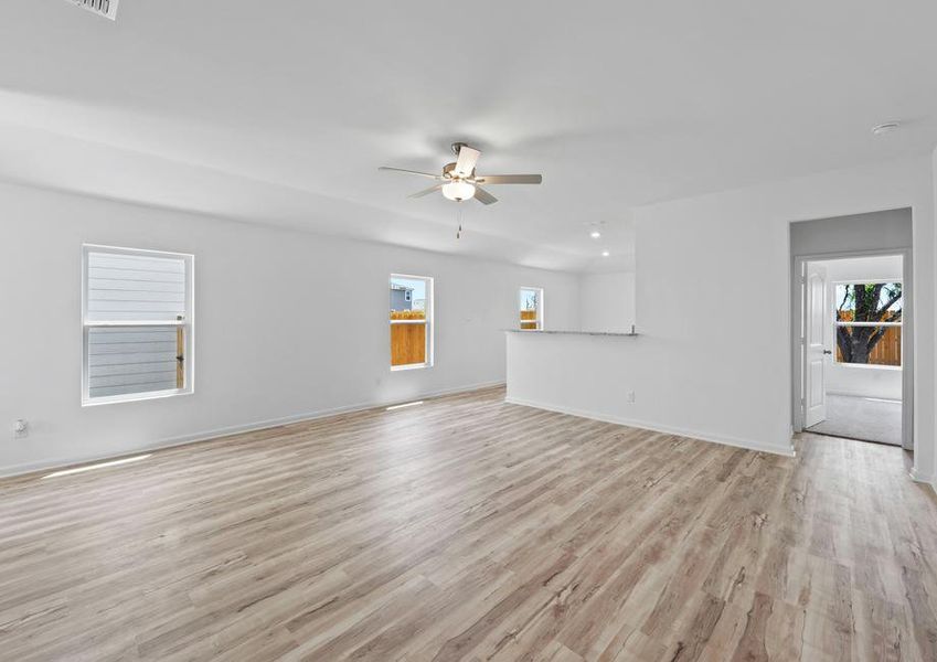 An open concept entertainment area with three windows and vinyl flooring