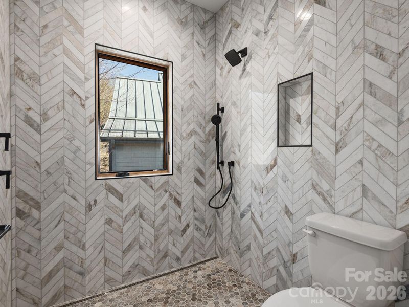 Representative photo from 50 Verde Drive showing the builder’s quality of construction and finish level, including a primary ensuite with fully tiled walk-in shower, designer fixtures, window for natural light, and detailed tile work extending from floor to ceiling.