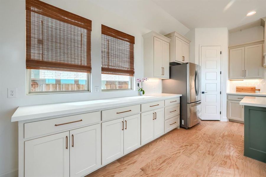 Kitchen with decorative backsplash, stainless steel fridge, and light wood-type flooring