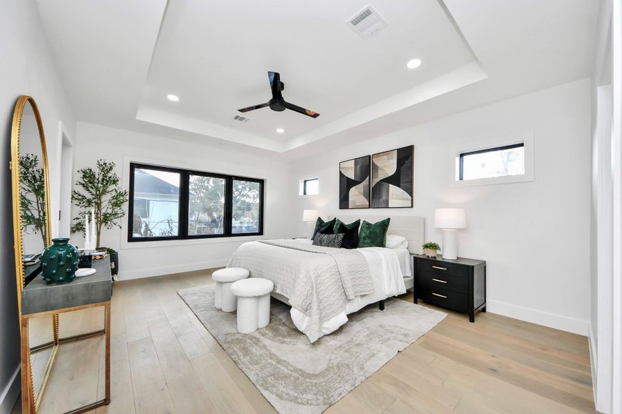 The primary bedroom is a serene sanctuary. Expansive windows fill the space with natural light, highlighting the refined finishes, neutral palette, and subtle architectural details that create a sense of calm and luxury.