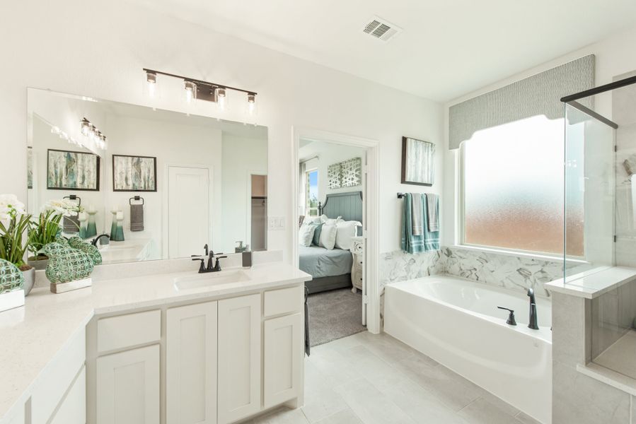 Master bathroom with white cabinets, soaking tub with marble surround, and glass shower enclosure Master bathroom with white cabinets, soaking tub with marble surround, and glass shower enclosure