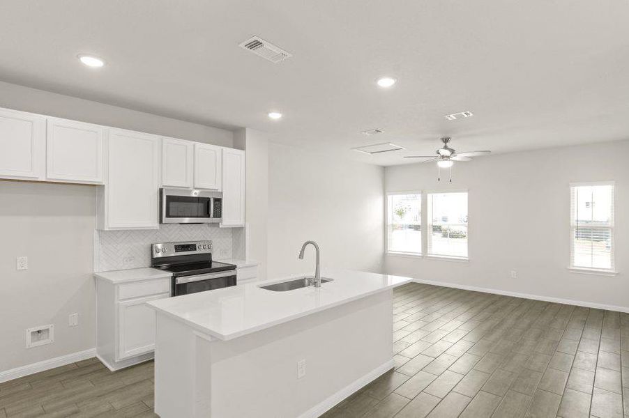 Kitchen featuring white cabinets, appliances with stainless steel finishes, wood tiled floors, a center island with sink, and recessed lighting Kitchen featuring white cabinets, appliances with stainless steel finishes, wood tiled floors, a center island with sink, and recessed lighting