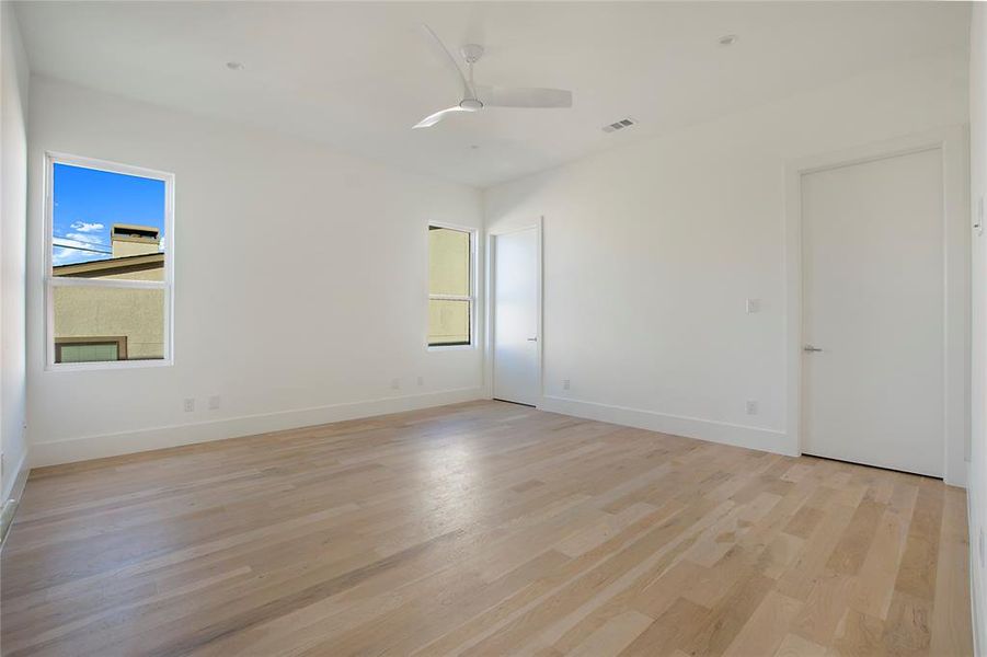 Spare room featuring ceiling fan, plenty of natural light, and light hardwood / wood-style flooring