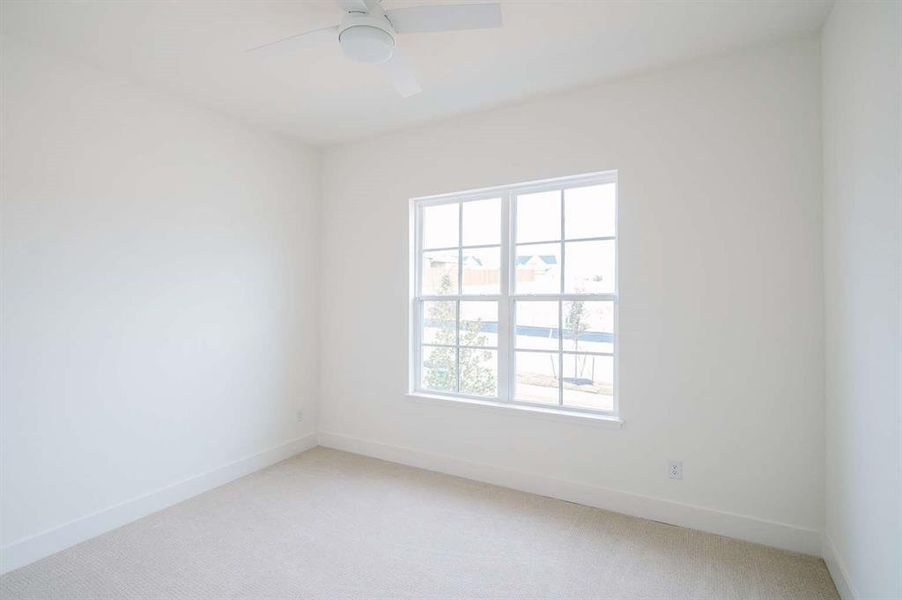 Spare room featuring carpet flooring, ceiling fan, and a healthy amount of sunlight