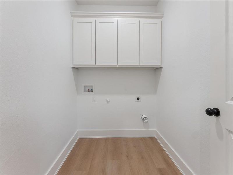 Laundry room with light wood-type flooring, hookup for a gas dryer, cabinet space, hookup for a washing machine, and electric dryer hookup