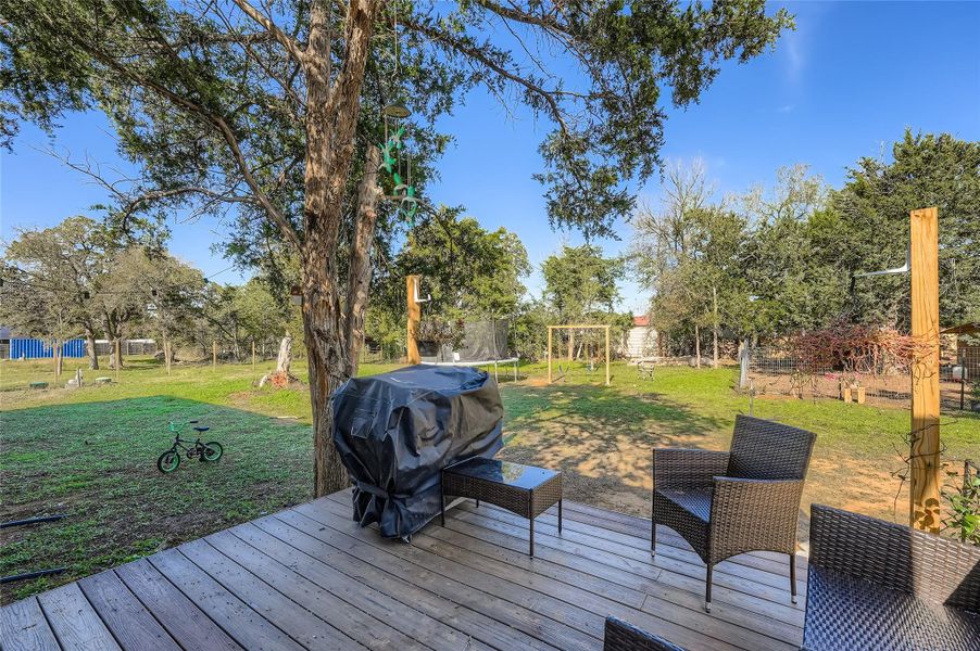 Deck featuring a lawn, area for grilling, and a trampoline Deck featuring a lawn, area for grilling, and a trampoline